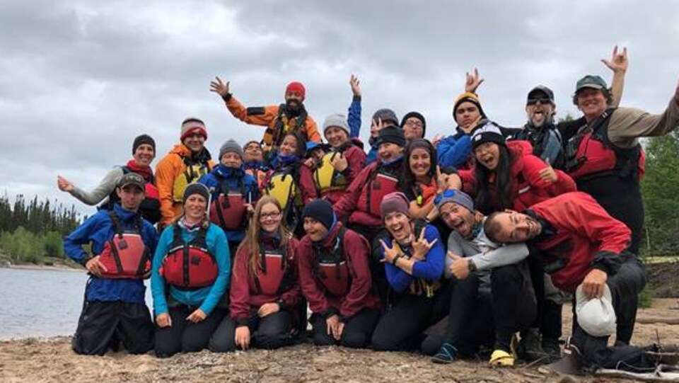 Des jeunes posent tout sourire devant un plan d'eau.