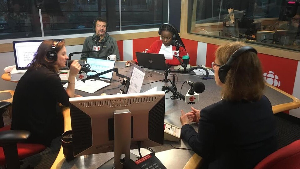Une femme et trois hommes sont assis autour d'une table dans un studio de radio