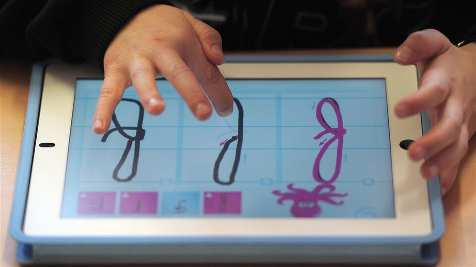 Un enfant apprend l'alphabet avec une tablette.