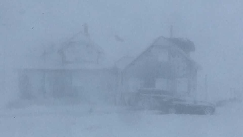 Une maison à peine visible dans la poudrerie.