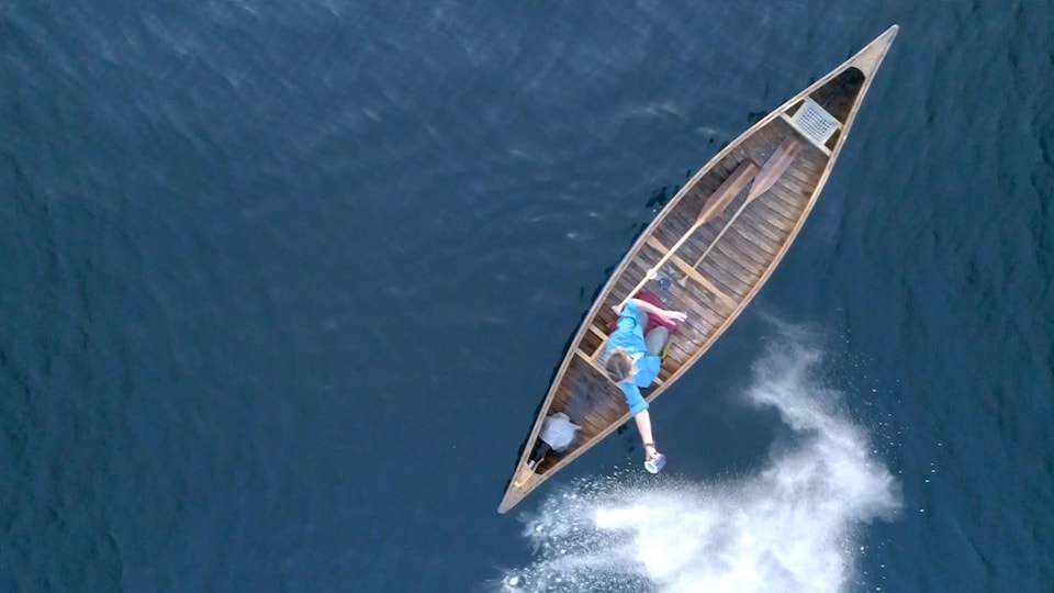 Une femme disperse des cendres dans l'eau depuis un bateau.