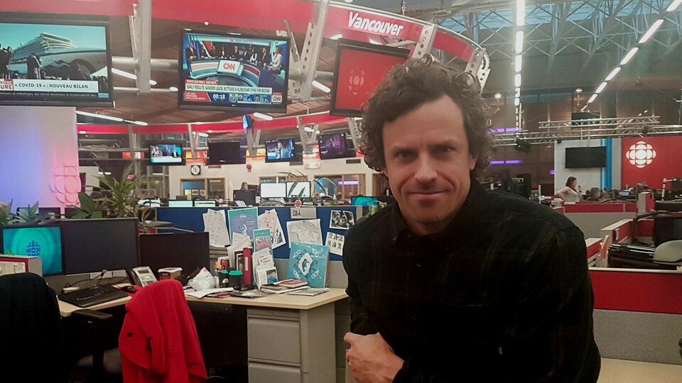 Le réalisateur Thomas Rinfret assis sur un fond de studio radio/télévion de Radio-Canada Vancouver.