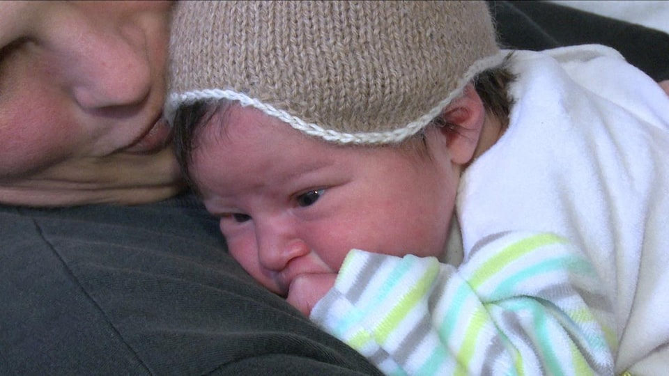 Un bébé naissant est dans les bras d'une femme.
