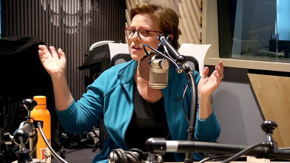 Maude Guérin est assise dans le studio de radio et parle au micro.