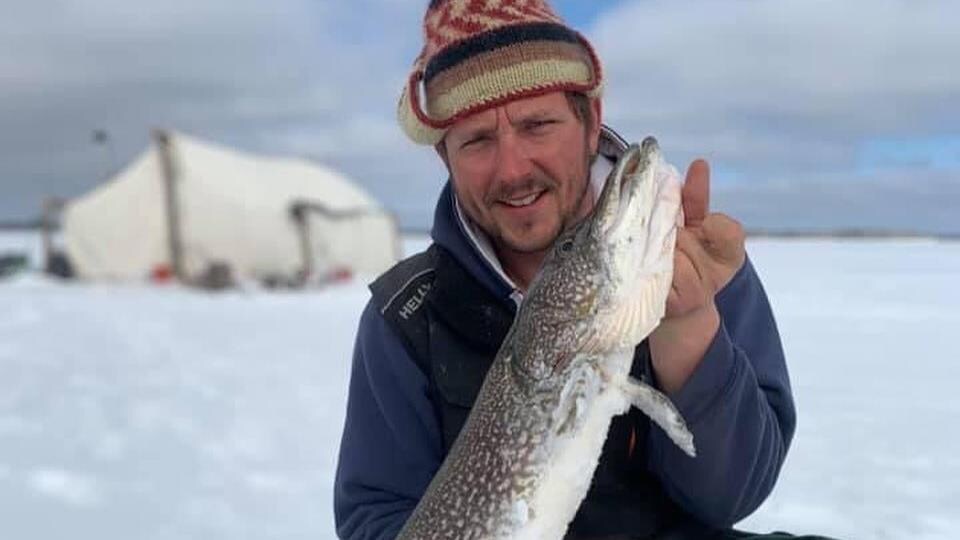 Le guide tient un poisson dans ses mains en hiver.