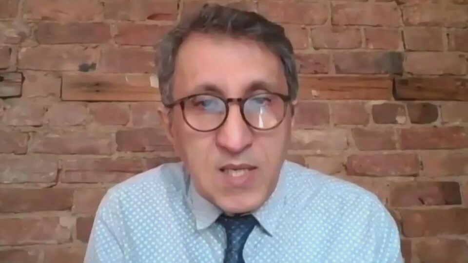 Amir Khadir parle devant un mur en briques.