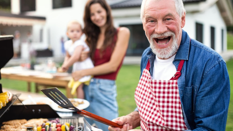 Un homme, une femme et un enfant devant un BBQ.