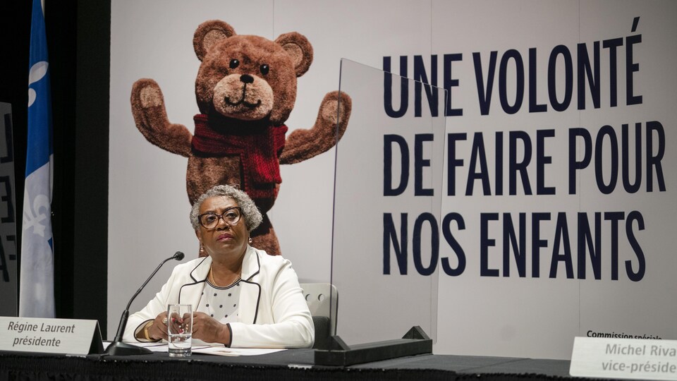 Régine Laurent, assise devant une image où est écrit « Une volonté de faire pour nos enfants ».