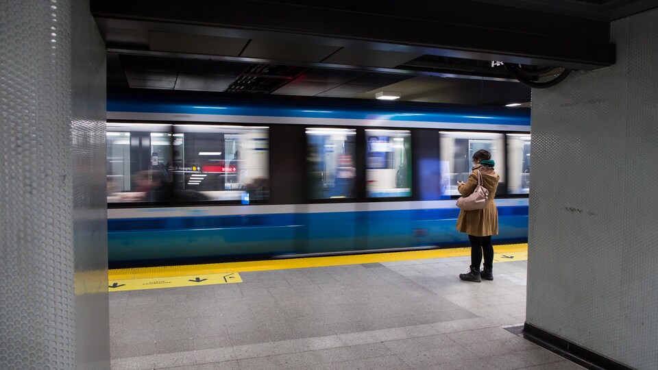 Une femme attend l'arrivée du métro sur le quai.