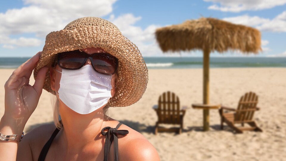 Une femme porte un masque sur la plage.
