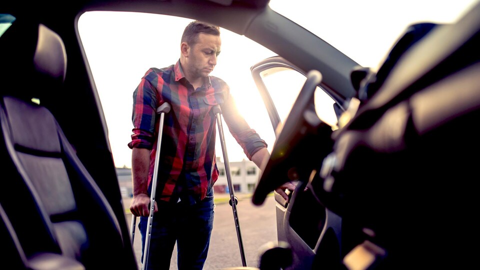 Un homme peine à entrer dans sa voiture.