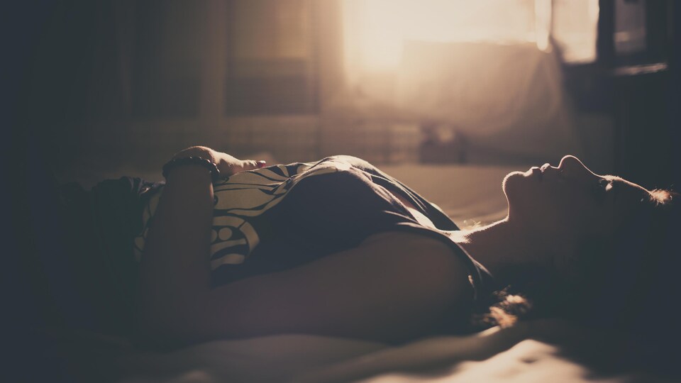 Une jeune femme est couchée dans une lit.