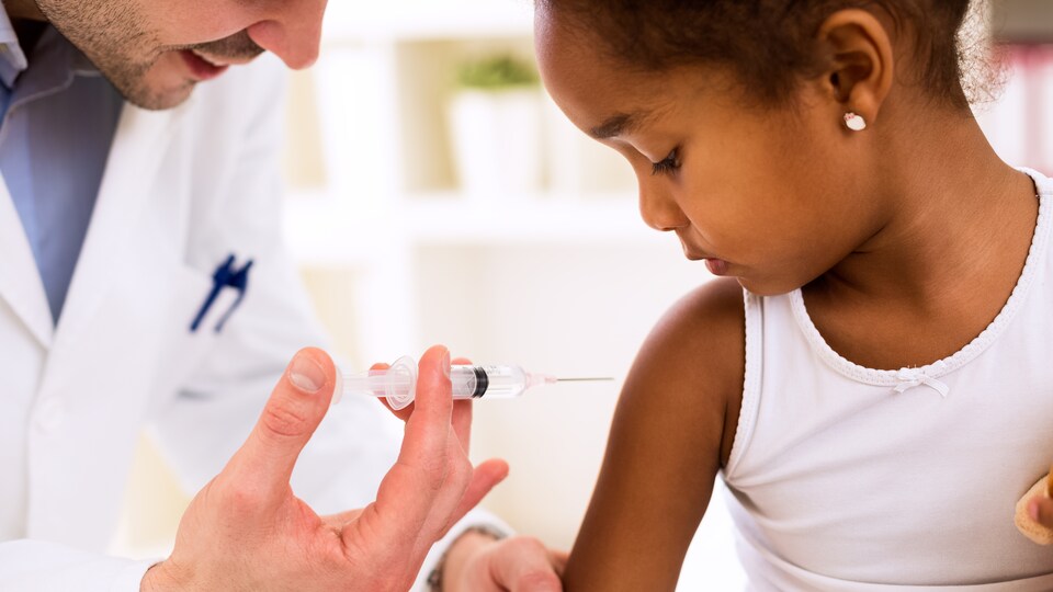 Une fillette est vaccinée par un médecin.