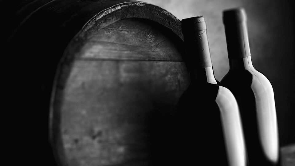 Deux bouteilles devant un tonneau de vin