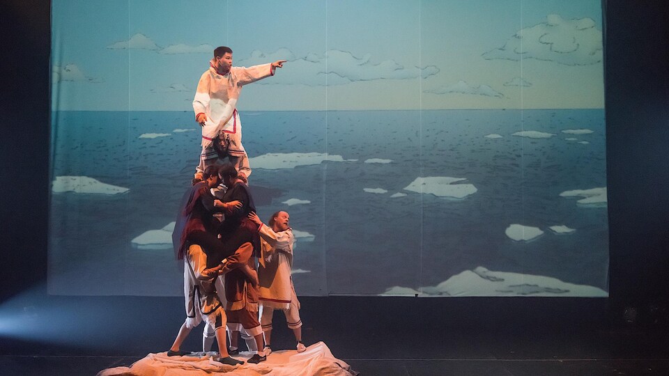 Des artistes forment une pyramide humaine sur scène.