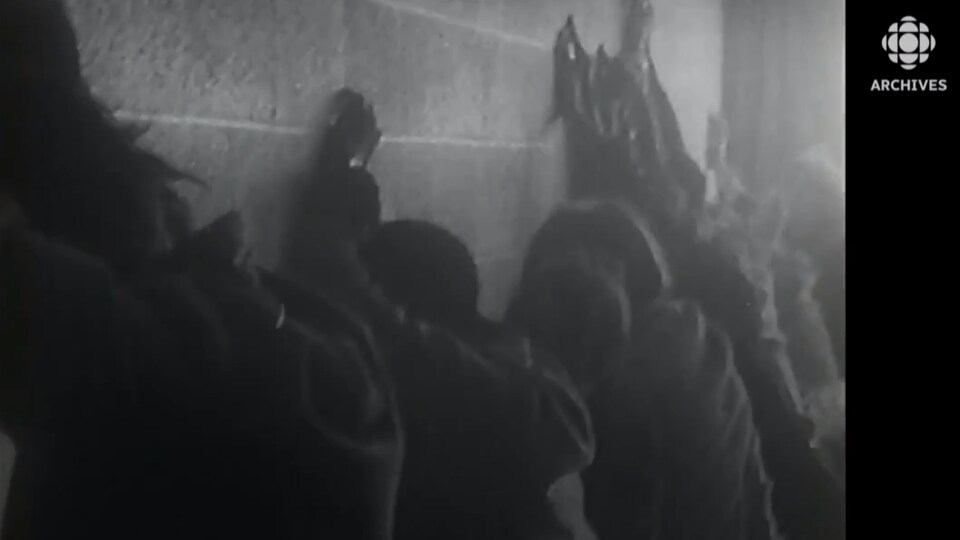 Des manifestants sont plaqués face à un mur durant l'émeute à l'Université Sir-George-Williams le 11 février 1969. 