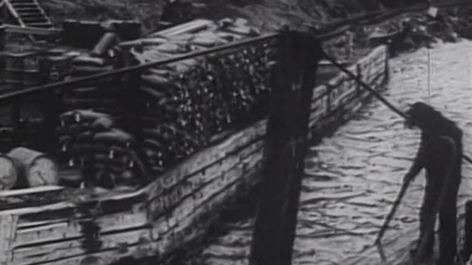 Un homme sur une barge flottant sur un lac.