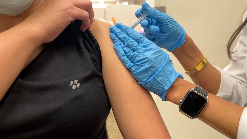Une personne reçoit une dose de vaccin dans l'épaule.