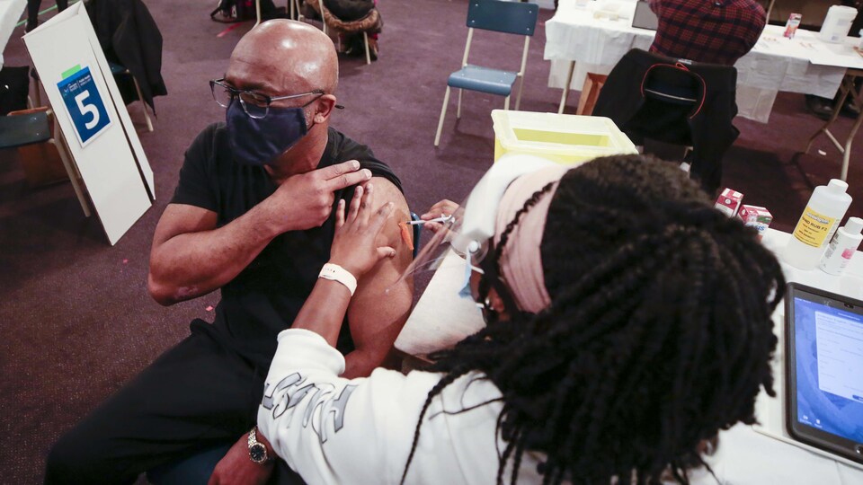 Un homme se fait vacciner par une infirmière.