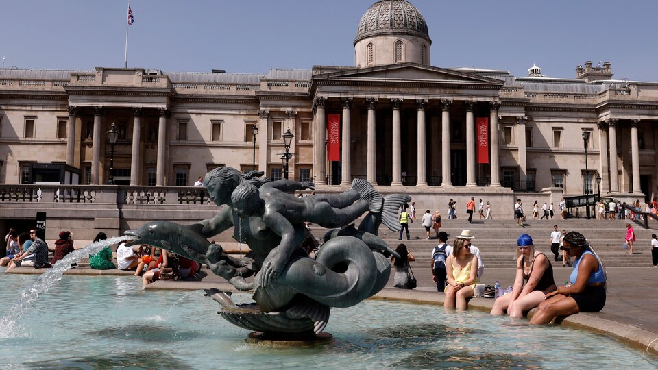 Des gens se rafraîchissent, les pieds dans l'eau de la fontaines de Trafalgar Square, dans le centre de Londres, le 17 juin 2022. 