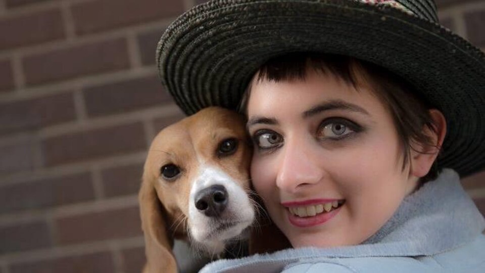 Valérie Prince portant un chapeau et tenant un chien beagle dans ses bras.