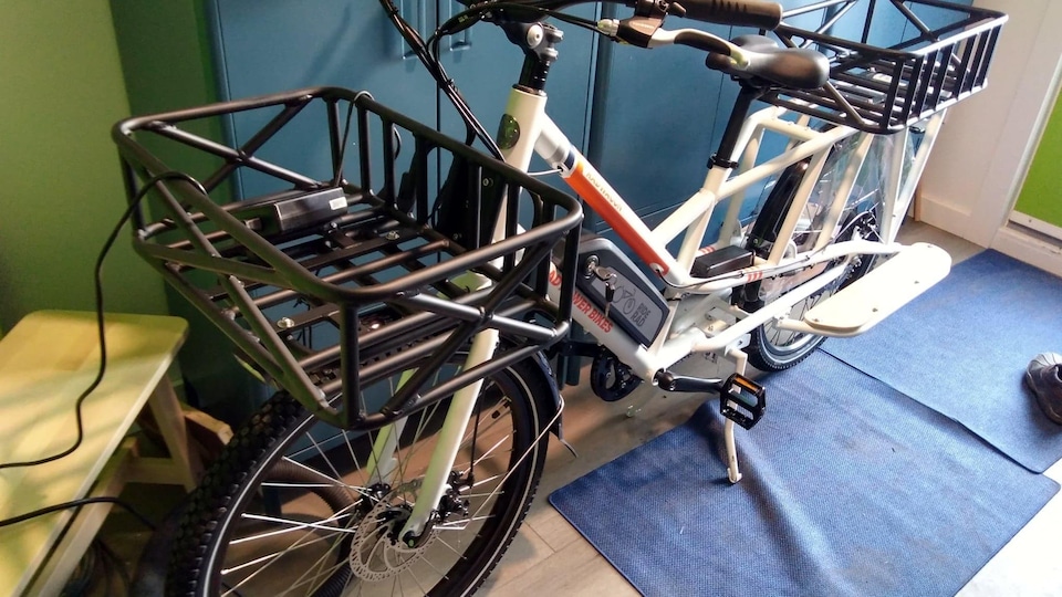 Un vélo électrique blanc doté de deux espaces cargos de chargement.