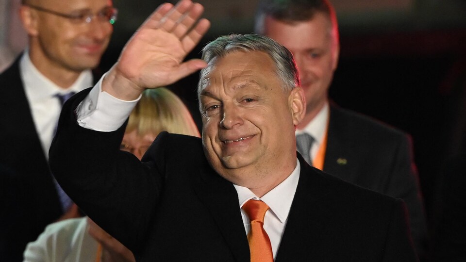Viktor Orbán faisant un salut de la main, sourire aux lèvres.