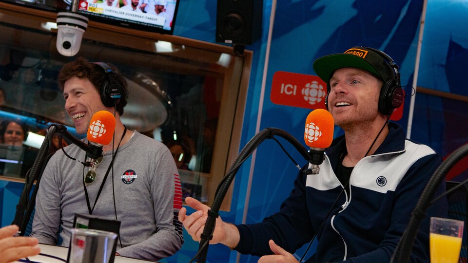 Deux hommes souriants en entrevue dans un studio de radio.
