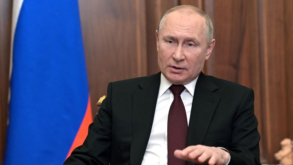 Portrait de Vladimir Poutine assis à un bureau.