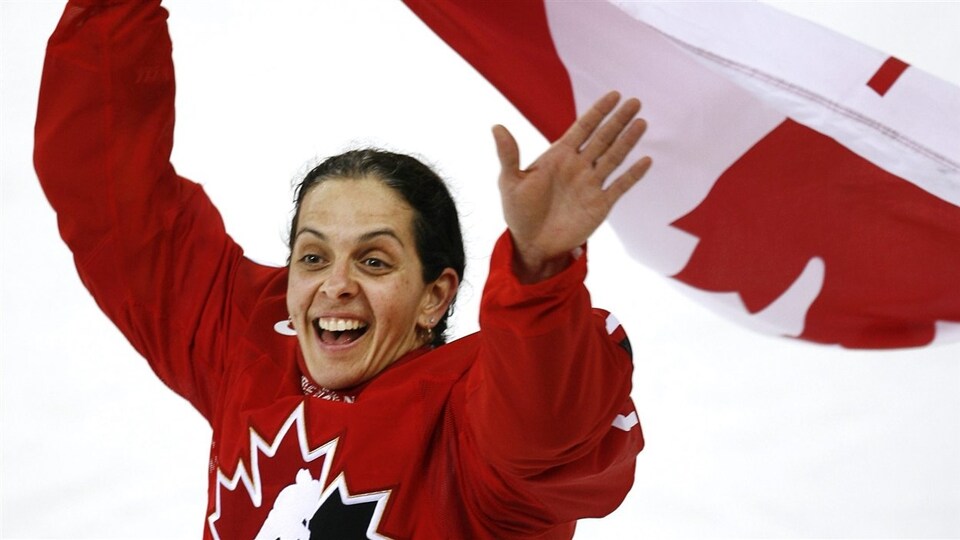 Elle sourit avec le drapeau canadien dans ses mains.