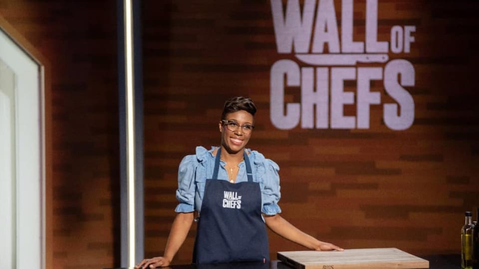 Une femme noire souriante portant un tablier sur le plateau de Wall of Chefs.