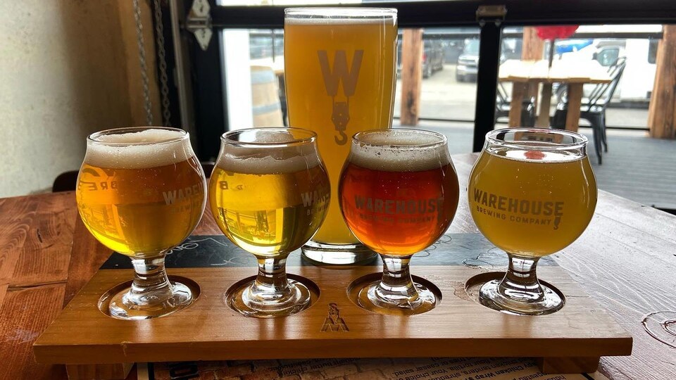 Cinq verres de bière de la brasserie Warehouse sur une table.