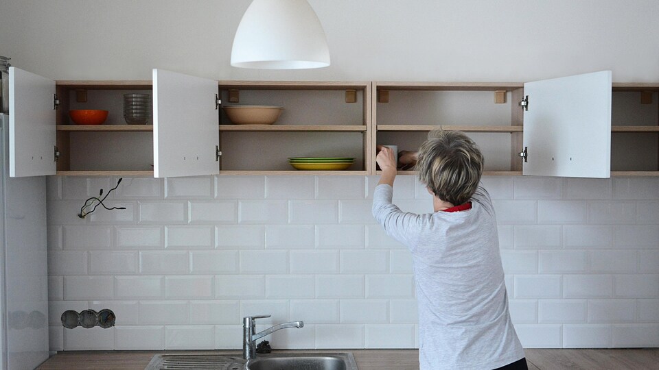 Une personne nettoie et range des armoires de cuisine.