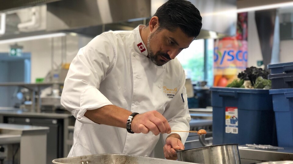 Le chef Samuel Sirois trempe un ingrédient dans du chocolat fondu.