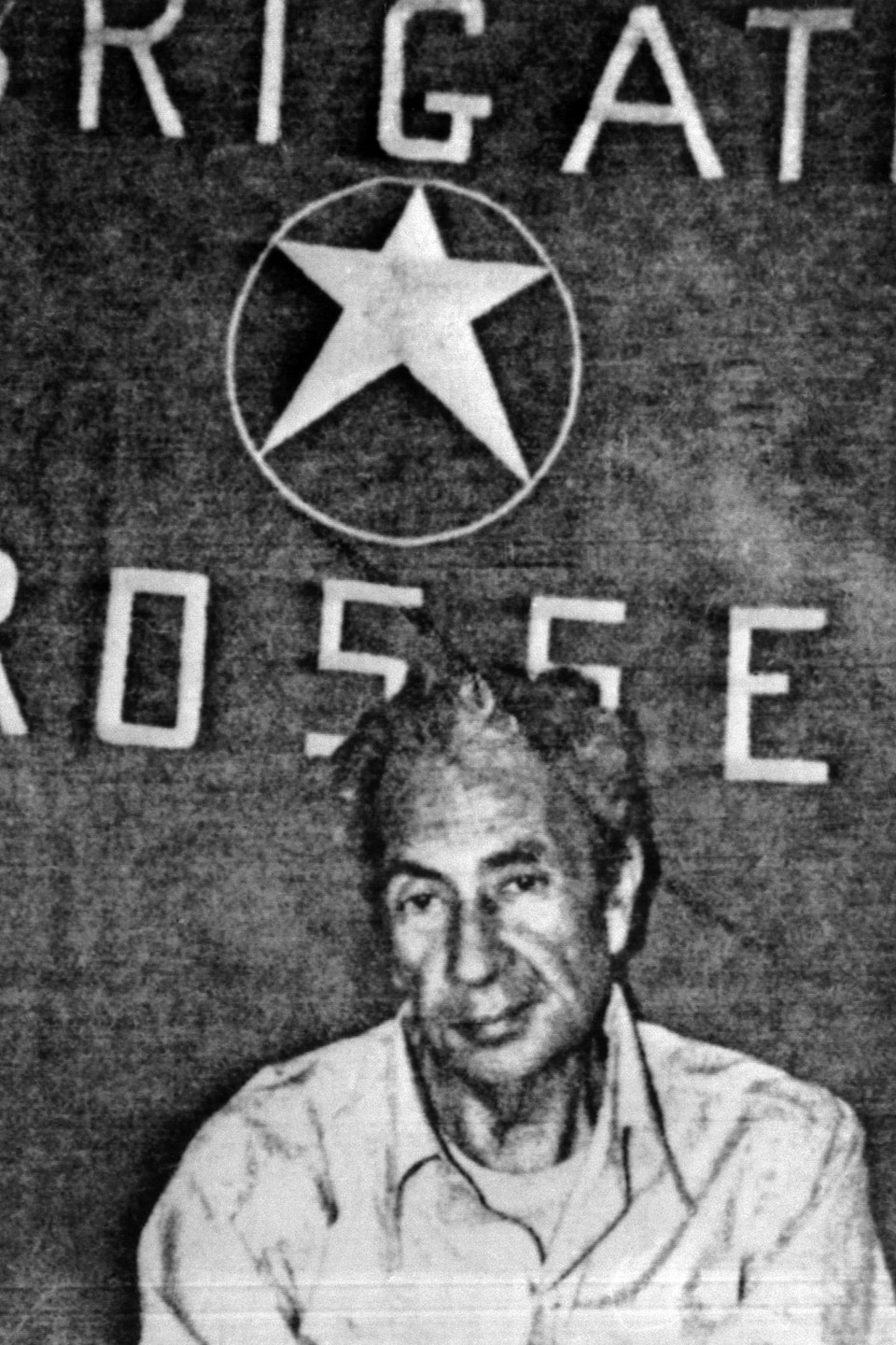 Aldo Moro pose devant une toile ornée d'une étoile et de l'inscription Rosse.
