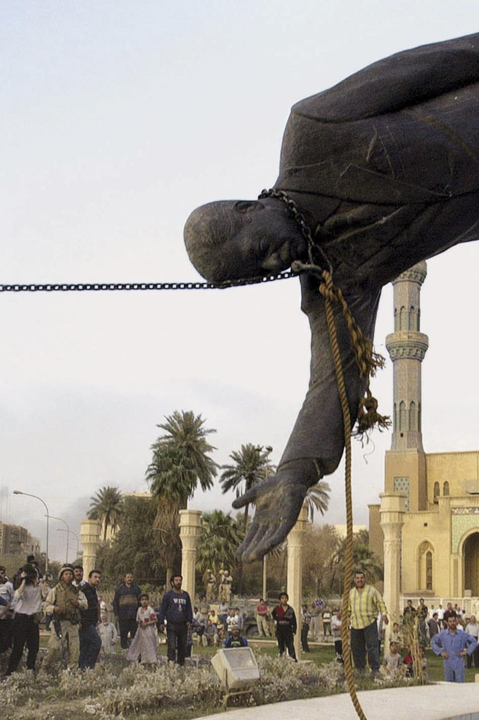 Une statue de Saddam Hussein tombe devant un soldat.