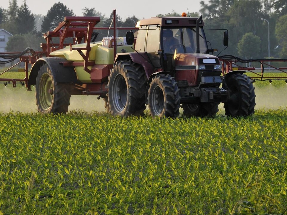 A tractor distributes pesticides in the field. 