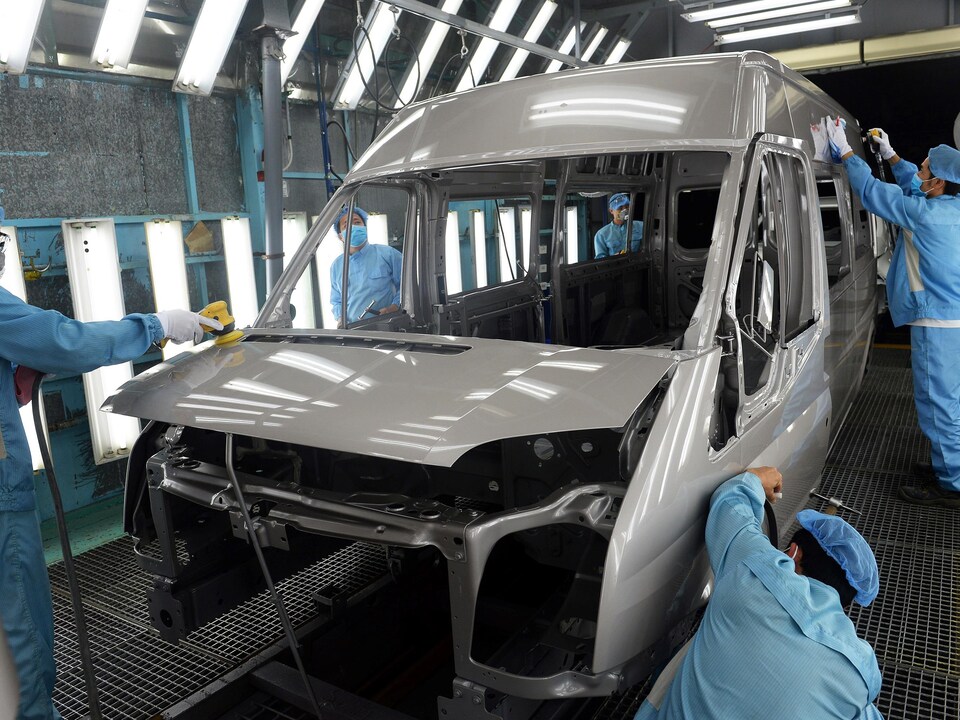 Five people dressed in blue are making the car.