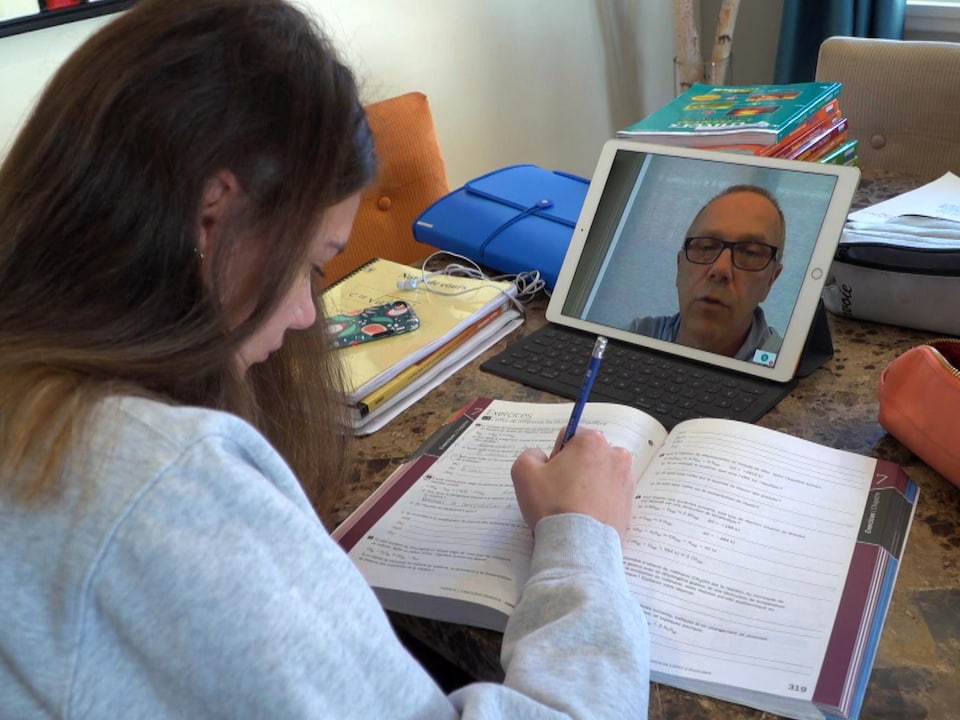 Una estudiante escucha a su maestra en una tableta electrónica mientras hace ejercicio.