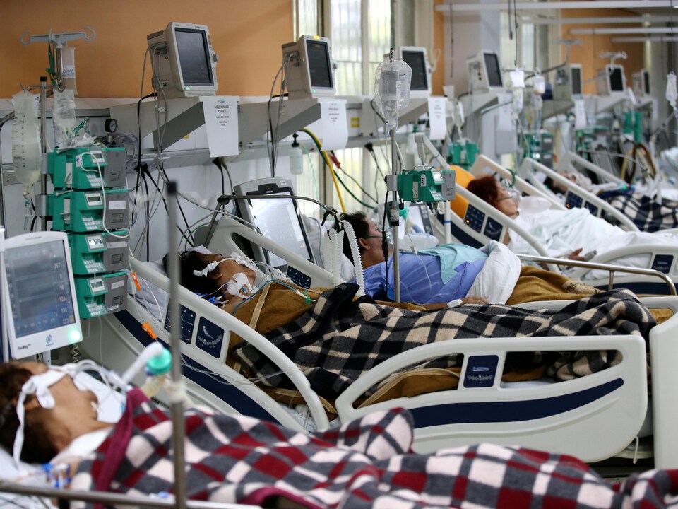 Des personnes intubées sont couchées sur des lits dans un hôpital.