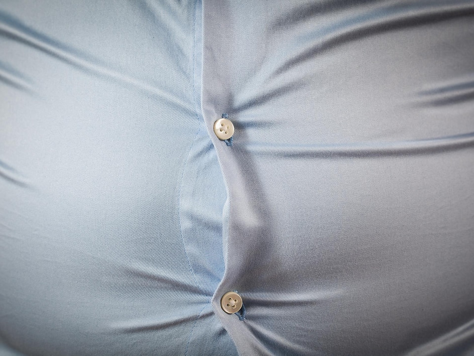 Une personne est aux prises avec un surplus de poids au niveau abdominal.
