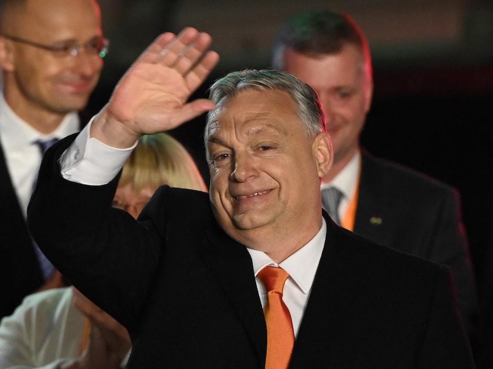 Viktor Orbán faisant un salut de la main, sourire aux lèvres.