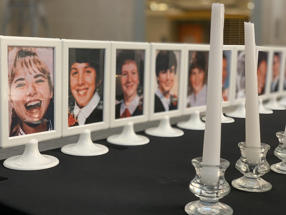 Les photos des 14 victimes de Polytechnique dans des cadres posés sur une table avec une rangée de chandelles blanches.