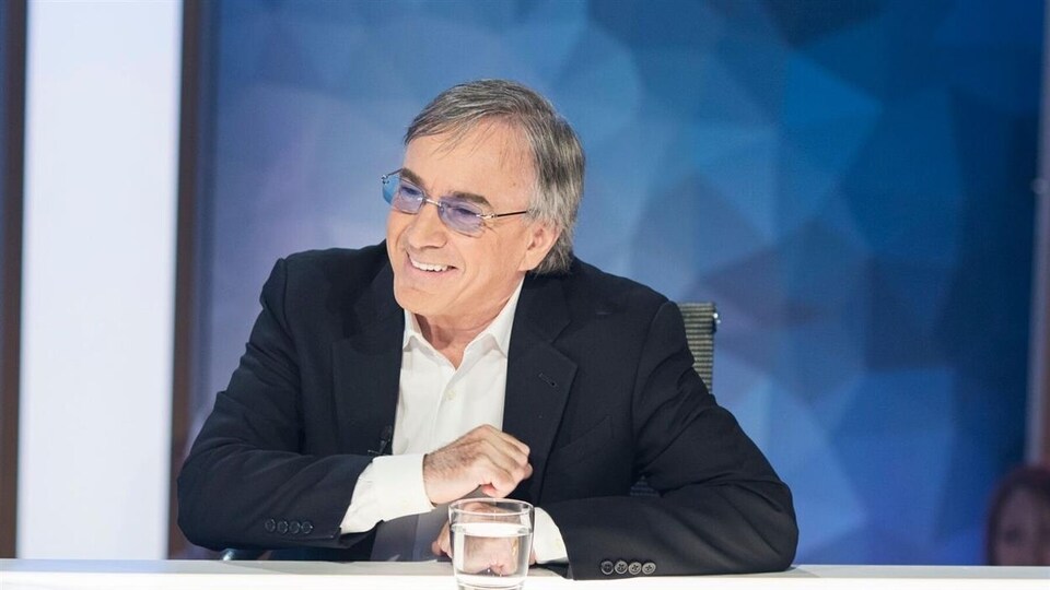 Assis devant une table, Daniel Lamarre sourit.