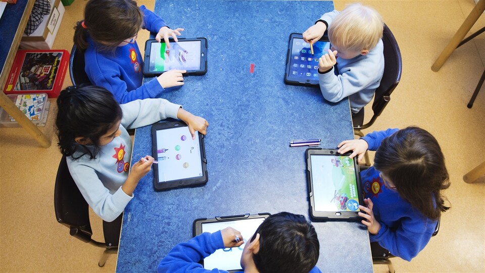 Des enfants apprennent en jouant sur une tablette.