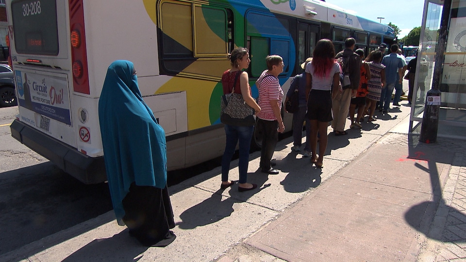 Une femme en niqab fait la file pour monter dans un autobus de la Société de transport de Montréal (STM).