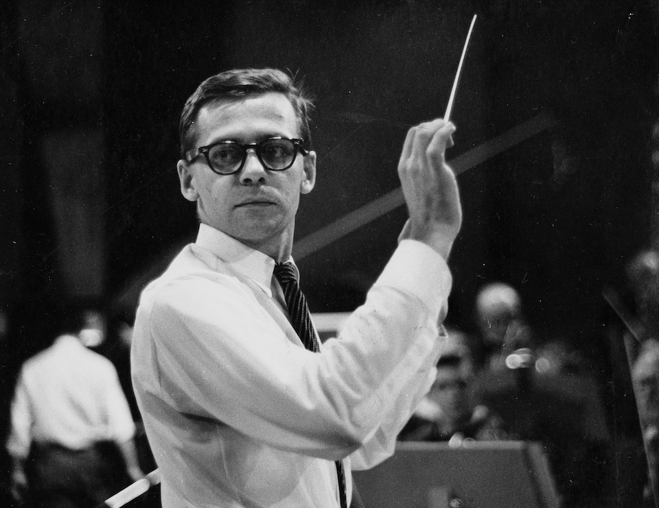 Photo en noir et blanc qui montre dans un studio de télévision, le chef
d'orchestre Pierre Mercure dirigeant les
musiciens qui sont devant lui.