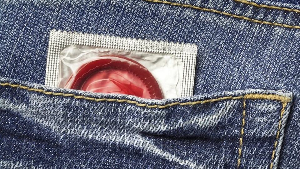 Un préservatif rouge dépasse d'une poche de jeans