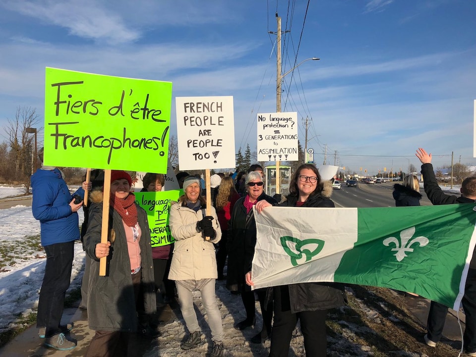 Des manifestants avec des enseignes et un drapeau franco-ontarien à Cambridge, en Ontario.