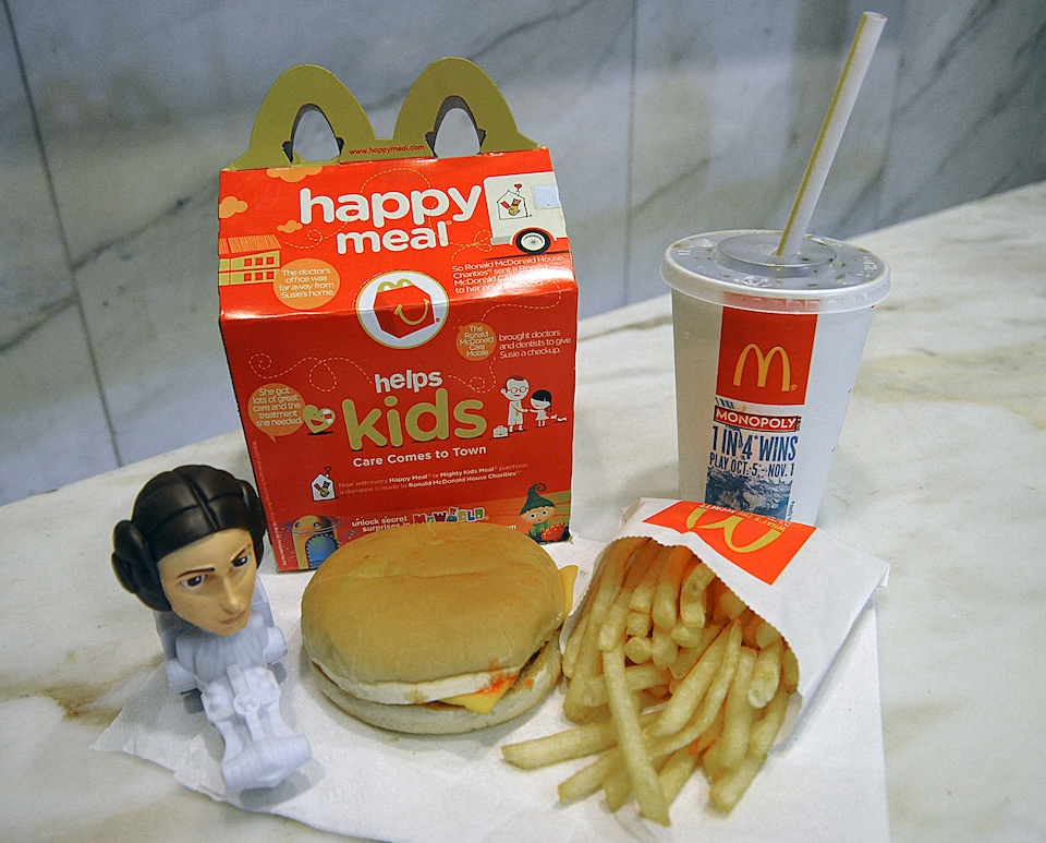 Un joyeux festin de la chaîne McDonald's sur une table, comprenant un jouet, une hamburger au fromage, une frite et une boisson gazeuse